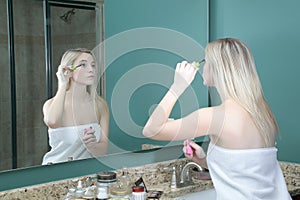 Girl doing makeup in front of mirror