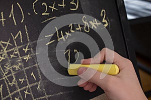 Girl doing math with chalk on blackboard.