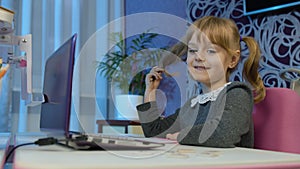 Girl doing online homework with teacher, using digital laptop computer at home, distance education