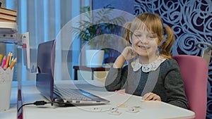 Girl doing online homework with teacher, using digital laptop computer at home, distance education