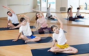 Girl doing Padmasana with side stretch during family yoga workout