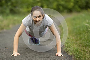 Girl doing push-ups from the ground, a warm up before your jog outdoors.