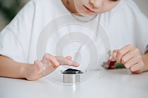 Girl doing science project, touching iron filings alligned with a magnet