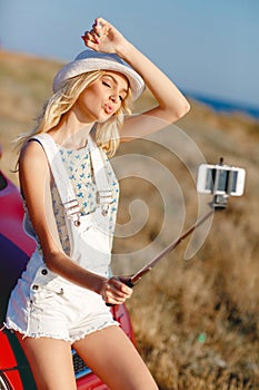 Girl doing selfie near the car at the beach