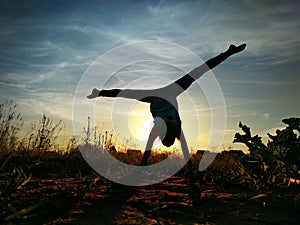 Girl doing split on handstand. A model stands on her hands, doing gymnastic splits against the blue sky