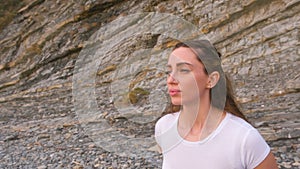 Girl is doing squats the bodyflex during breathing exercises on the rock background. Face close-up.