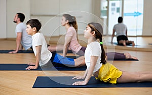 Girl doing stretching asana Upward Facing Dog during family yoga workout