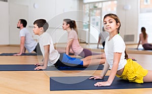 Girl doing stretching asana Upward Facing Dog during family yoga workout