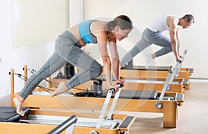 Girl doing stretching exercises on reformer in pilates studio photo