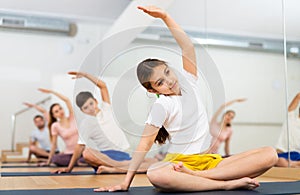 Girl doing stretching in Padmasana pose with brother and parents in yoga studio