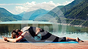 Girl doing stretching while sitting on a twine in full length against a background of beautiful nature