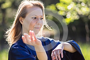 A girl doing tai Chi exercises in a green Park on a Sunny day close up