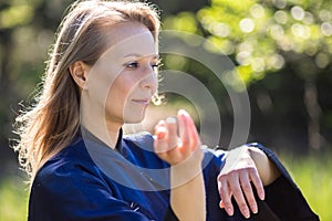 A girl doing tai Chi exercises in a green Park on a Sunny day close up