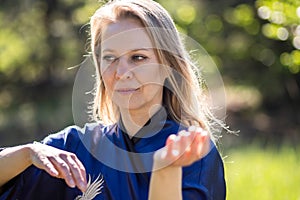 A girl doing tai Chi exercises in a green Park on a Sunny day close up