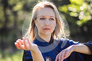 A girl doing tai Chi exercises in a green Park on a Sunny day close up