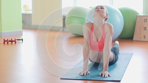 Girl doing warming up exercise for spine, backbend, arching stretching her back working out at home or yoga class.