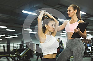 Girl doing weight exercises with assistance of personal trainer