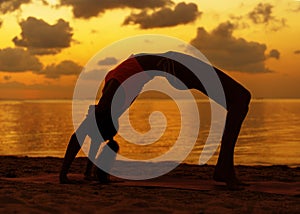 Girl doing yoga on the beach at sunset