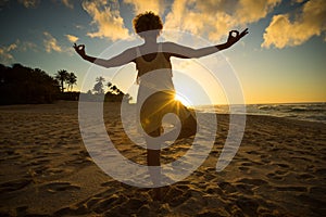 Girl doing yoga at the beach at sunset