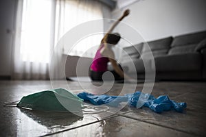 Girl doing yoga at home after breaking free from the protective mask and gloves from coronavirus, covid-19