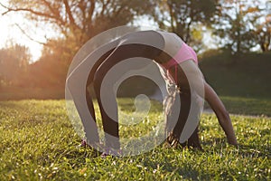 Girl is doing yoga, standing in bridge pose. Setu Bandhasana. with sunset on background