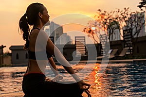 Girl doing yoga at sunset in Thailand near the pool