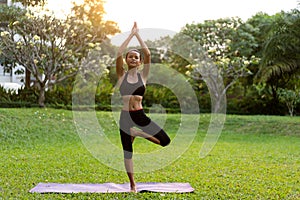 Girl doing yoga at sunset in Thailand in the park