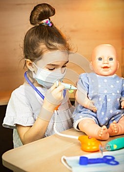 A girl with a doll plays doctor, makes a syringe inoculation in the hand. Vaccination, vaccination calendar, vaccine, profession