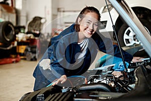 This girl dont mind getting grease under her nails. a female mechanic working on a car in an auto repair shop.