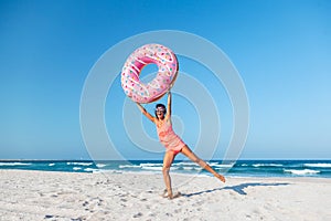 Girl with donut lilo on the beach