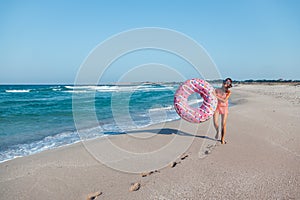 Girl with donut lilo on the beach