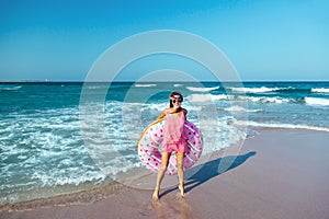 Girl with donut lilo on the beach