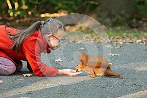 A girl with down syndrome feeds a squirrel in the forest