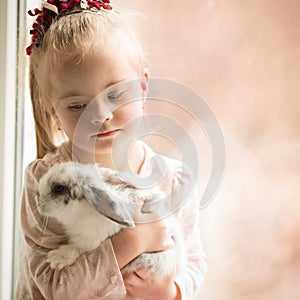 Girl with Down syndrome hugs rabbit