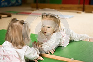 Girl with Down syndrome looks at his reflection in the mirror