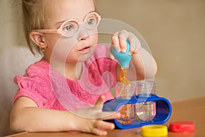 Girl with Down syndrome pours water by means of enema tubes in a test tube photo