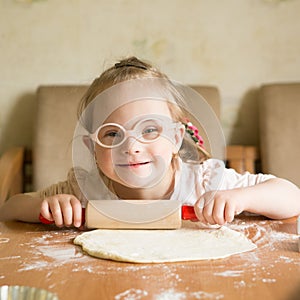 Girl with down syndrome unrolls dough