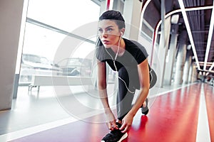 Girl down to do shoelaces at fitness gym before running exercise workout