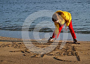 Girl drawing in beach sand