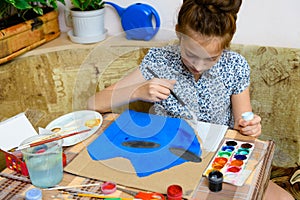 A girl drawing blue gouache cardboard, artistic creation at home, makes creative artwork