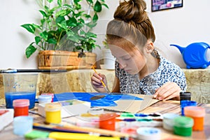 A girl drawing blue gouache cardboard, artistic creation at home, makes creative artwork