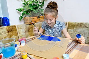 A girl drawing blue gouache cardboard, artistic creation at home, makes creative artwork