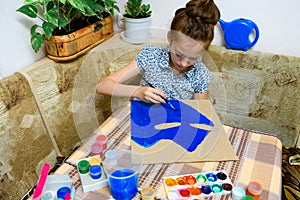 A girl drawing blue gouache cardboard, artistic creation at home, makes creative artwork