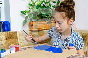 A girl drawing blue gouache cardboard, artistic creation at home, makes creative artwork