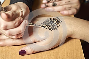 Girl drawing patterns by henna on the hands