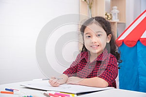 Girl drawing picture and smiles on table at home