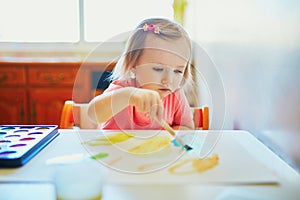 Girl drawing rainbow with colorful aquarelle paints