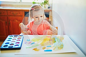 Girl drawing rainbow with colorful aquarelle paints