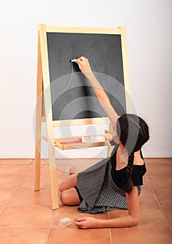 Girl drawing or writing on black blackboard