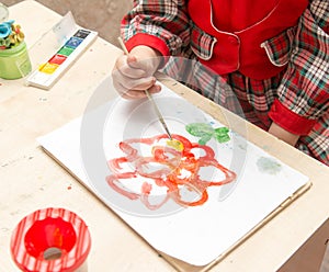 A girl draws a drawing with paints on a sheet